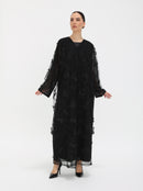 Person wearing a black dress with sheer sleeves on a white background